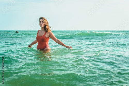 Beautiful young European woman with an orange swimsuit at the sea in Cádiz