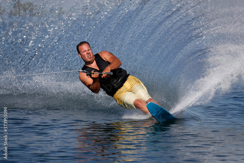 man slalom water skiing  and making spray.