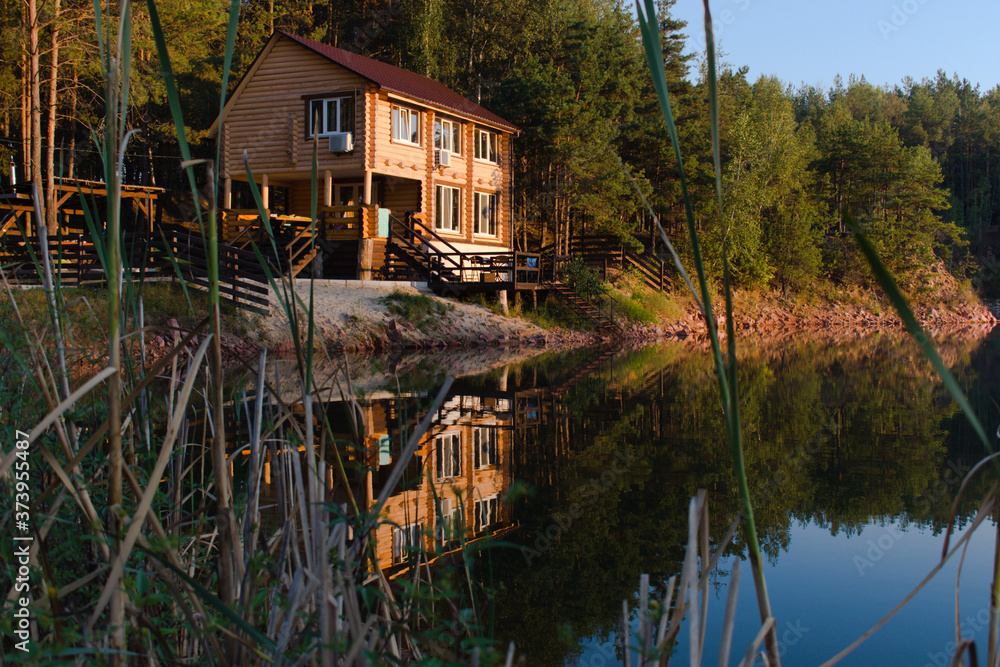 Obraz premium country house with reflection in the water in the warm light of the rising sun