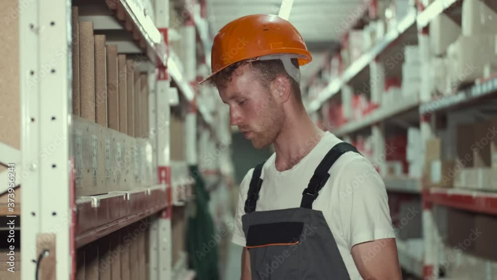 Enginner is working at the ware house. The worker is checking the materials and looking at the data in a clipboard. Enginner is working at the ware house. The worker is checking the materials and looking at the data in a clipboard.