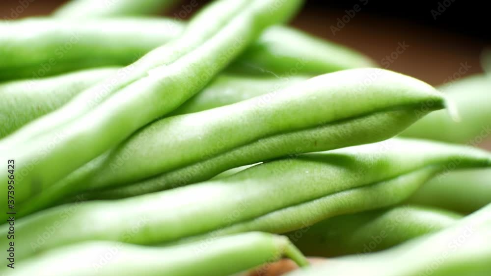 Raw fresh uncooked string beans on wooden kitchen surface close up selective focus dolly left Raw fresh uncooked string beans on wooden kitchen surface close up selective focus dolly left