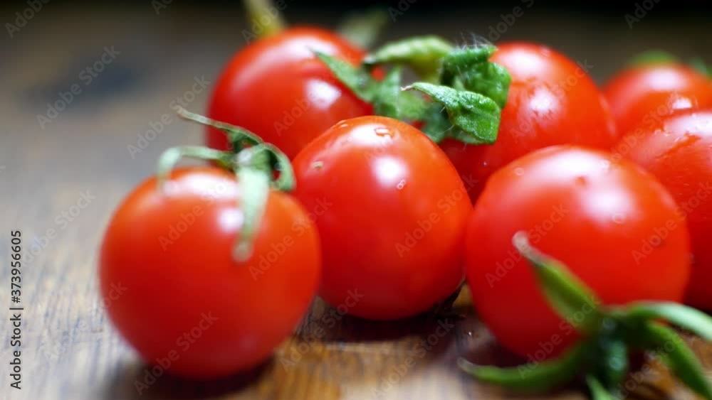 Raw fresh tiny red juicy wet cherry tomatoes on wooden kitchen surface selective focus dolly right closeup Raw fresh tiny red juicy wet cherry tomatoes on wooden kitchen surface selective focus dolly right closeup