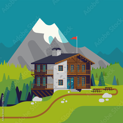 High quality flat design vector illustration of green mountain meadow with wooden lodge resort with high snow covered peak and spruce trees on background