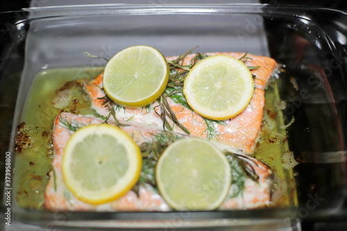 Baked salmon fillets in a glass baking tray resting on the stove.