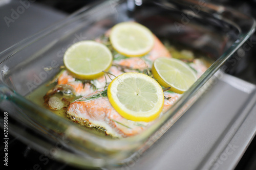 Baked salmon fillets in a glass baking tray resting on the stove. photo