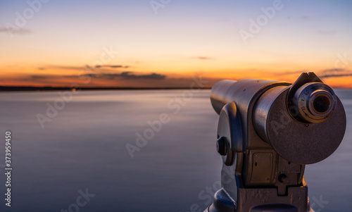 A telescope on a lookout at a beautiful sunset and a long exposure of the water on the sea.