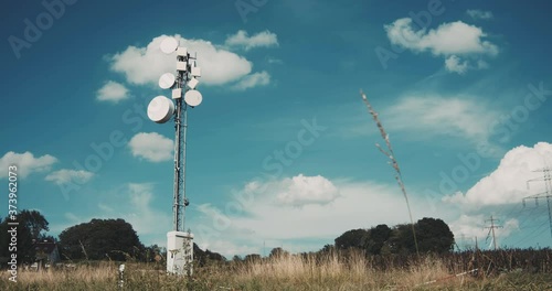 Large antenna mast with various telecommunication antenna in a field against a blue sky. Telecommunication tower with 5G cellular network antenna.