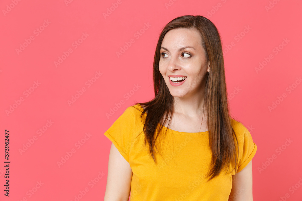 Excited cheerful beautiful attractive charming pretty young brunette woman 20s wearing yellow casual t-shirt posing standing and looking aside isolated on pink color wall background studio portrait. Excited cheerful beautiful attractive charming pretty young brunette woman 20s wearing yellow casual t-shirt posing standing and looking aside isolated on pink color wall background studio portrait.