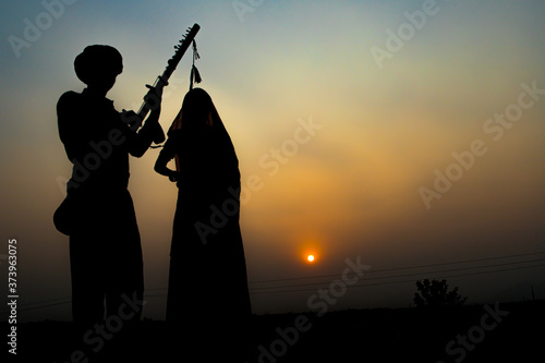 silhouette of Folk Musicians performing on Sand Dunes at sunset