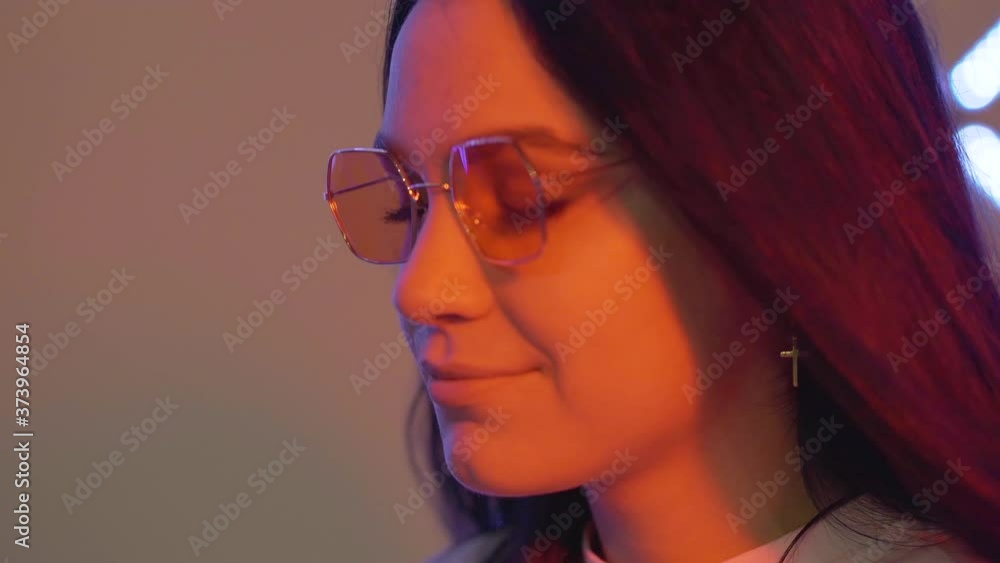 Close-up of stoned young woman taking pill in night club. Portrait of relaxed Caucasian drug addict partying in neon lights. Female junkie in sunglasses having harmful addiction. Close-up of stoned young woman taking pill in night club. Portrait of relaxed Caucasian drug addict partying in neon lights. Female junkie in sunglasses having harmful addiction.