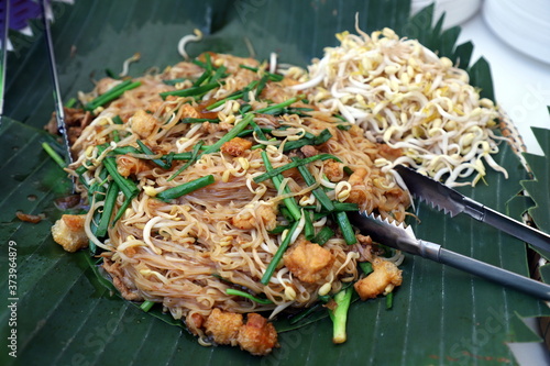 Korat Pad Mee is a local dish from Nakhon Ratchasima, Thailand, looks similar to Pad Thai in the central region on banana leaves, with a stainless steel tongs placed next to it. Selective focus. photo