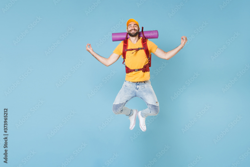 Full length portrait Smiling young traveler man with backpack isolated on blue background. Tourist traveling on weekend getaway. Tourism discovering hiking concept. Jump hold hands in yoga gesture. Full length portrait Smiling young traveler man with backpack isolated on blue background. Tourist traveling on weekend getaway. Tourism discovering hiking concept. Jump hold hands in yoga gesture.