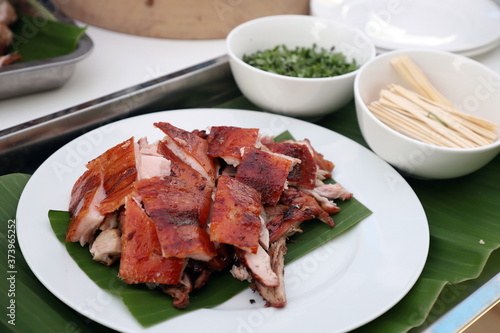 Foto Roasted suckling pig, crispy skin, cut into pieces Looks delicious on a white plate, beneath the pork with banana leaves
