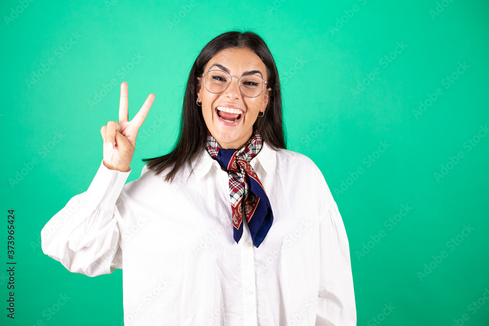 Young beautiful business woman over isolated green background showing and pointing up with fingers number two while smiling confident and happy Young beautiful business woman over isolated green background showing and pointing up with fingers number two while smiling confident and happy
