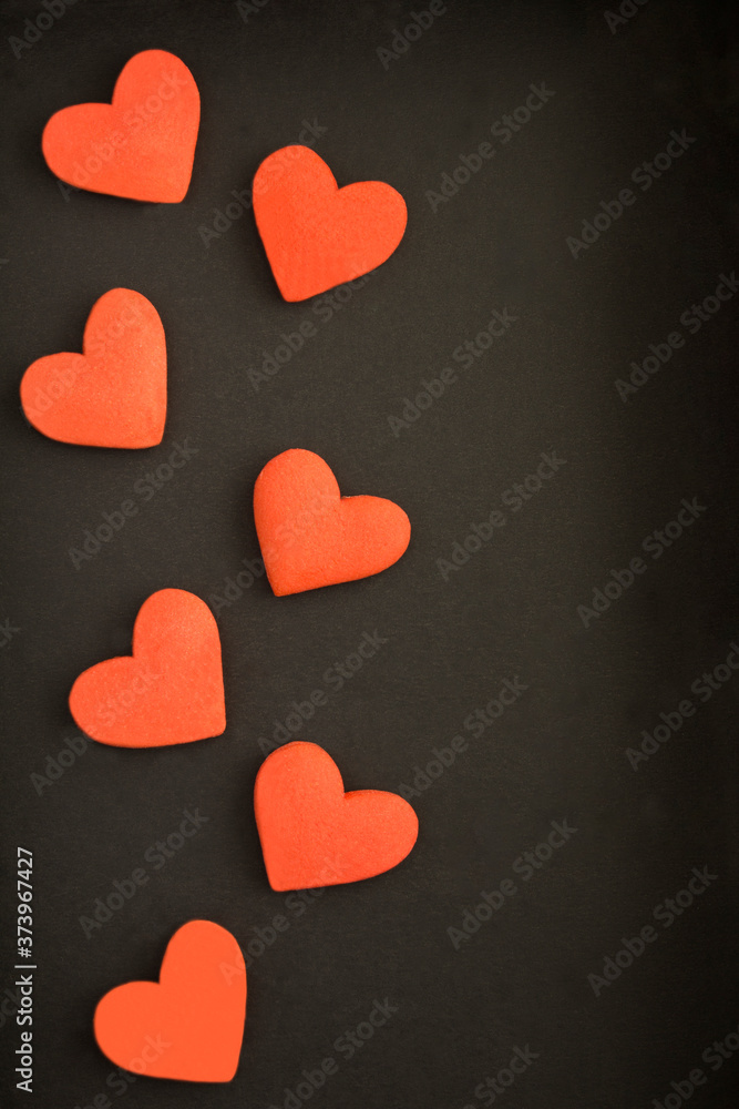 Top view of red hearts shaped cookies on the black surface. Location vertical.