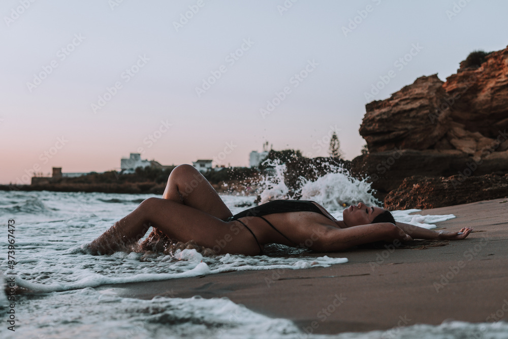 young woman in a black swimsuit posing on the beach young woman in a black swimsuit posing on the beach