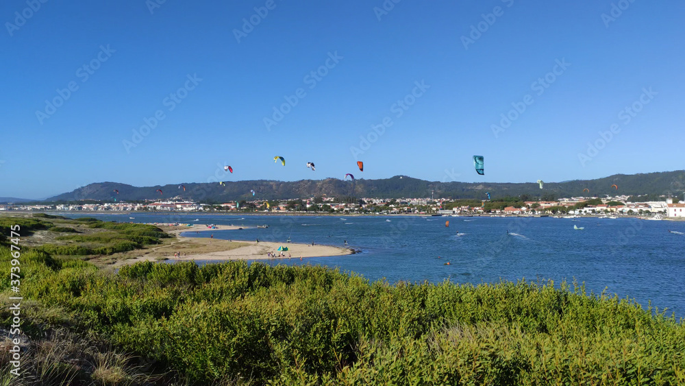 People practicing kitesurf. Kitesurfers on the mouth of the Cavado River in Esposende, Portugal. Esposende it's renowned by kite-surfers as one of the best places to kitesurf.