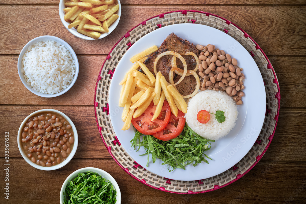 Brazilian food dish. Beans, rice, meat, chips, cabbage, tomatoes, onions. Executive dish. Dish done. Top view. Isolated on wooden background. Brazilian food dish. Beans, rice, meat, chips, cabbage, tomatoes, onions. Executive dish. Dish done. Top view. Isolated on wooden background.