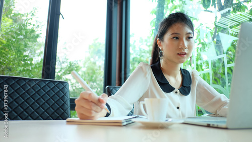 Young attractive businesswoman working with laptop and document while sitting at the office desk in modern office. photo