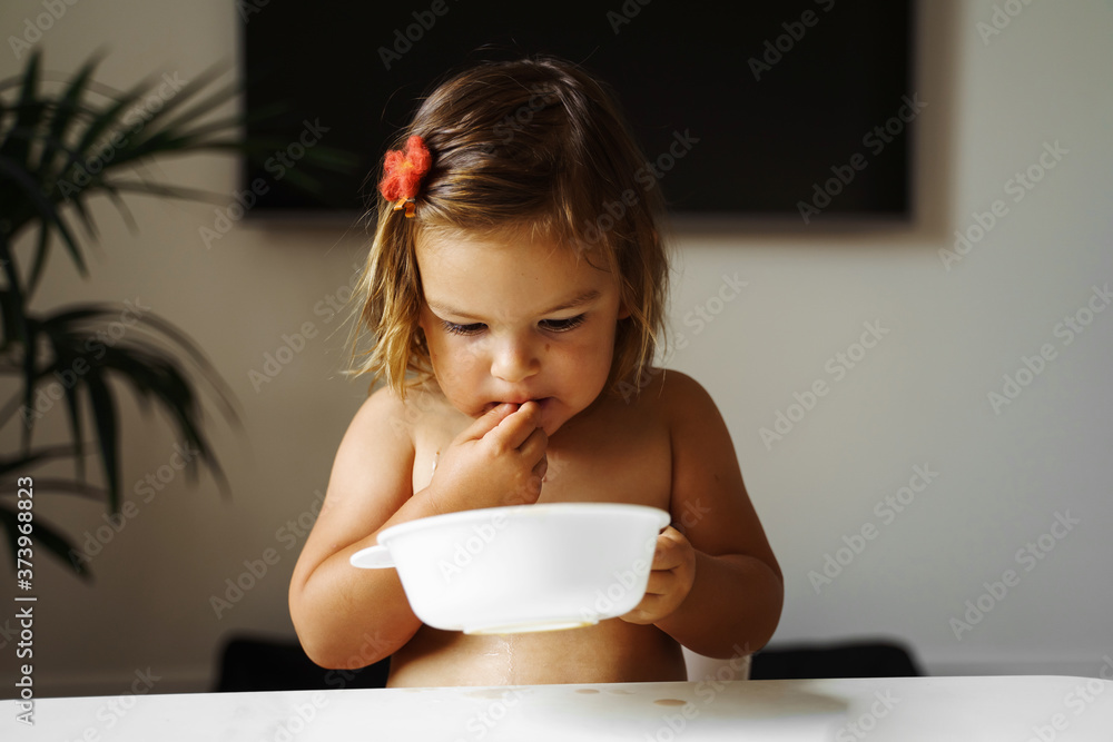 Toddler girl eating cookie and drink juice. Snack food for child. Home lifestyle Toddler girl eating cookie and drink juice. Snack food for child. Home lifestyle