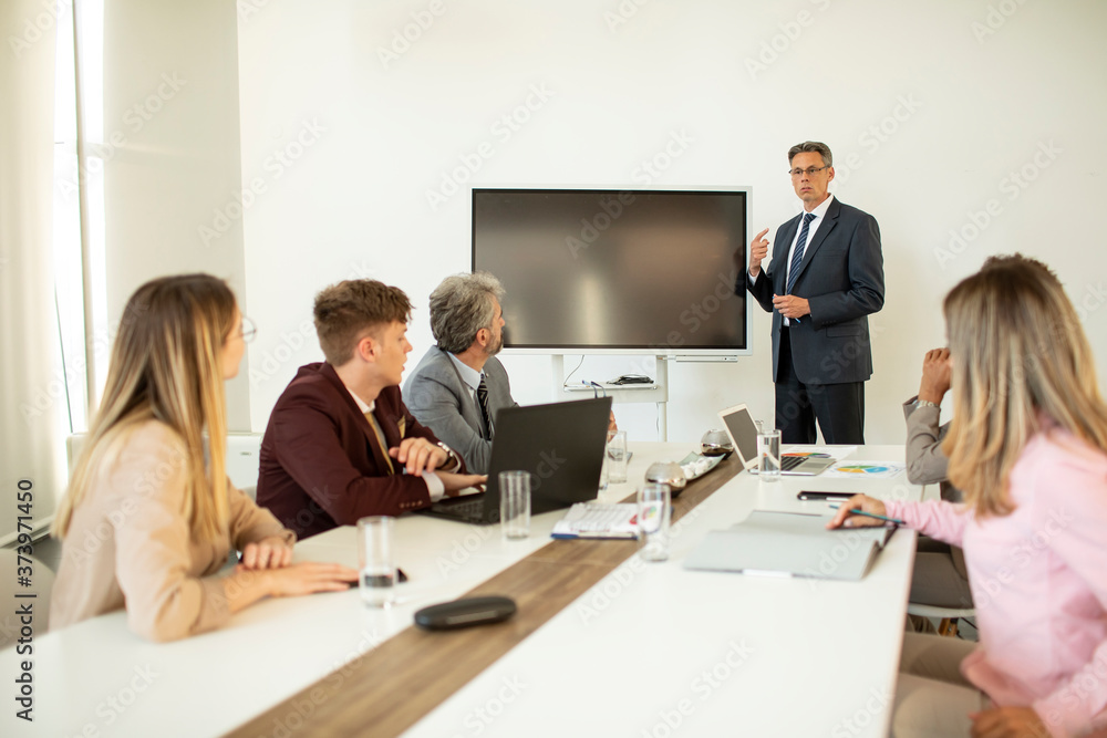 Mature businessman explaining strategy to group of multiethnic business people while working on new project Mature businessman explaining strategy to group of multiethnic business people while working on new project