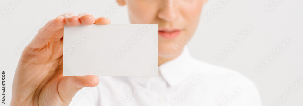 girl in a white office shirt holds out a business card. close portrait. girl in a white office shirt holds out a business card. close portrait.