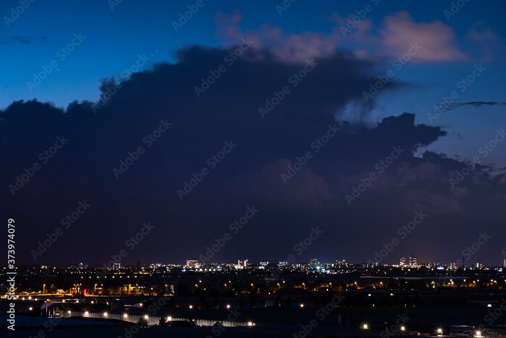 Silhouette of a storm cloud in the evening light. Dutch city of The Hague in the foreground.