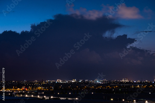 Silhouette of a storm cloud in the evening light. Dutch city of The Hague in the foreground.