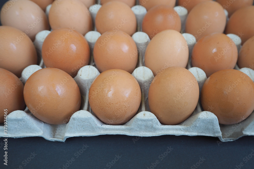 front of a large cardboard container with yellow eggs on a black background side view. lots of raw eggs front of a large cardboard container with yellow eggs on a black background side view. lots of raw eggs
