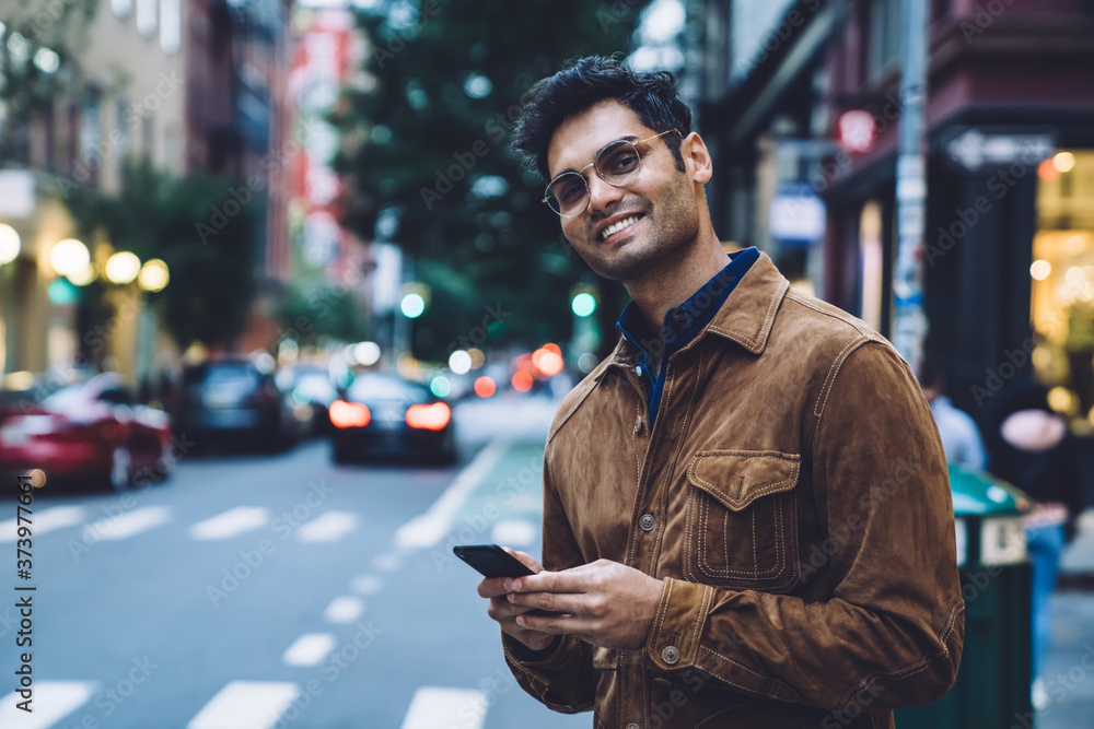Cheerful ethnic young man with smartphone on street Cheerful ethnic young man with smartphone on street