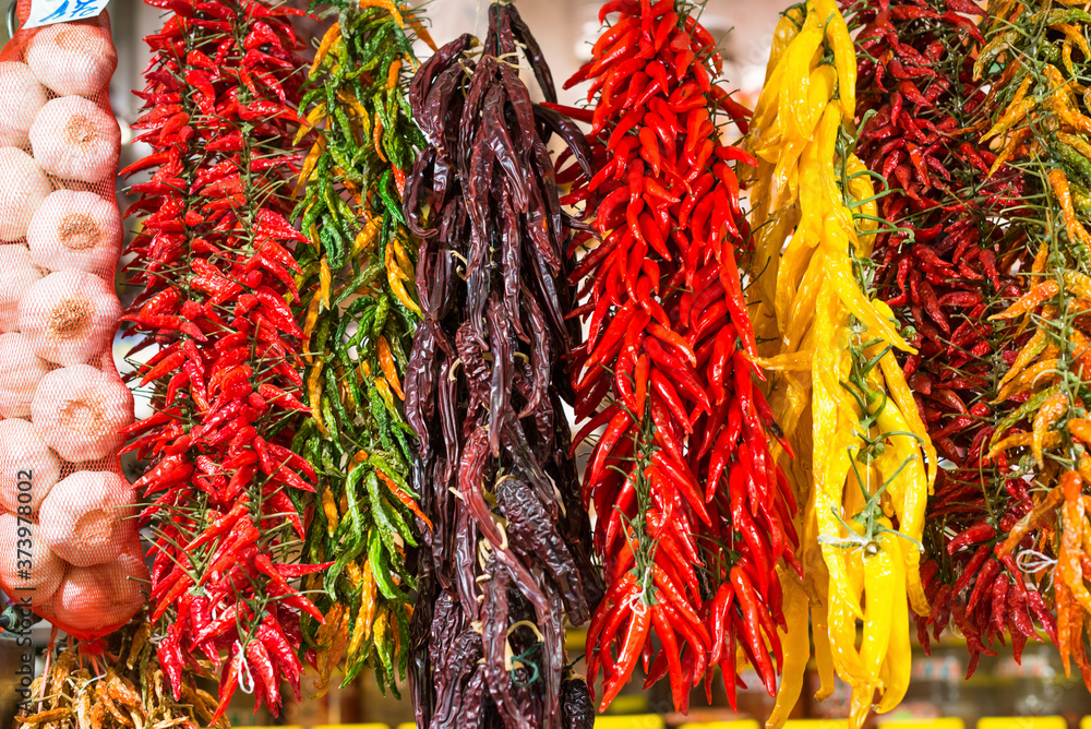 Naklejka premium A variety of chillies hanging on display at La Boqueria market in Barcelona, Spain.