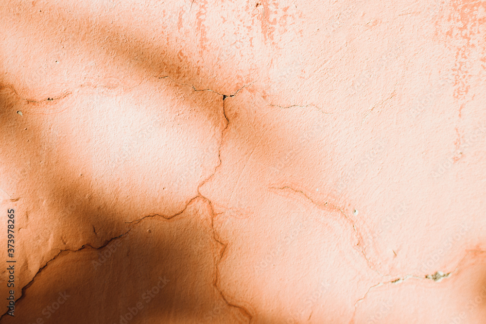 An old wall with orange cracks. Plaster is falling off.Shadows fall on the wall. An old wall with orange cracks. Plaster is falling off.Shadows fall on the wall.