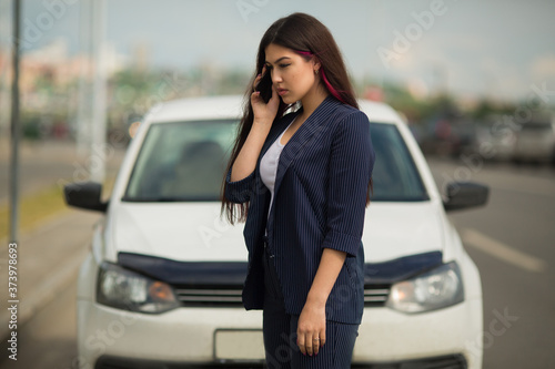 beautiful young woman with phone near car
