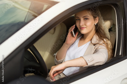 beautiful young woman driving a car with a phone in hand
