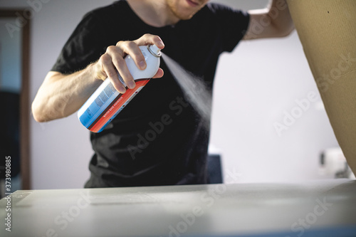 Bilde på lerret Selective focus of artisan using adhesive spray while working on screen printing