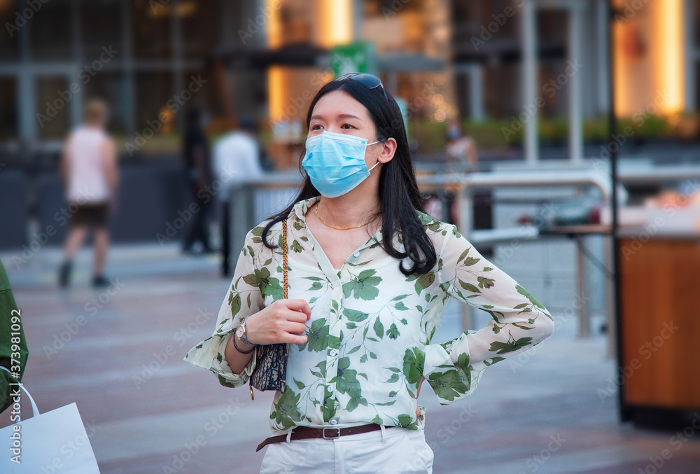 Asian woman wearing face mask in outdoors shopping mall