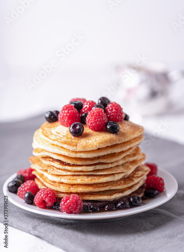Homemade pancakes with raspberries and blueberries on grey napkin.