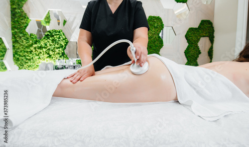 A young pretty girl is enjoying a professional vacuum massage at the Spa. Body care. Beauty salon photo