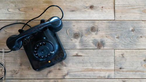 Flat lay of old rotary black antique vintage telephone on wood background copy space historical communication