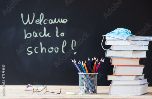 back to school concept during covid - pile of books and medical mask