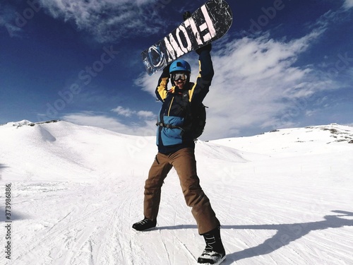 Snowboardzista triumfujący z deską ponad głową na stoku we francuskich Alpach 