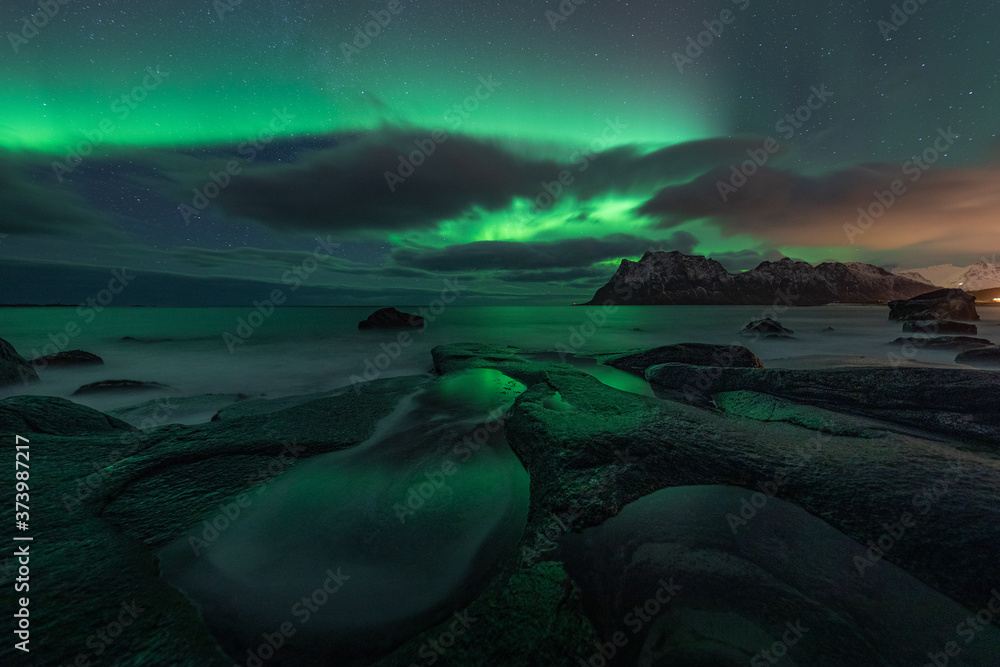 Northern lights (Aurora Borealis) over the starry night sky. Uttakleiv beach in Lofoten, Norway