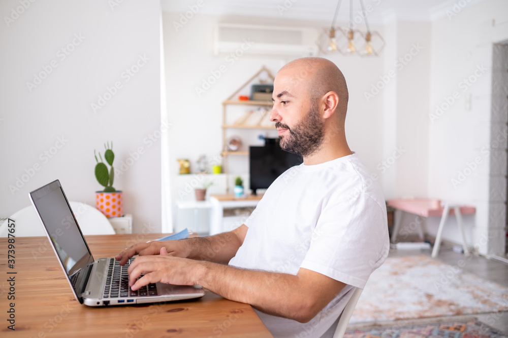 young man working remotely with leptop at his home. Distance Learning.