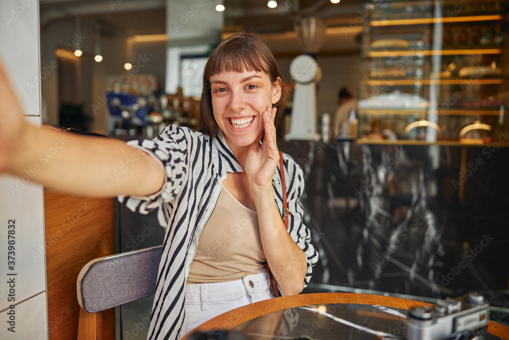 Joyful female photographer with outstretched hand in cafe close up Joyful female photographer with outstretched hand in cafe close up