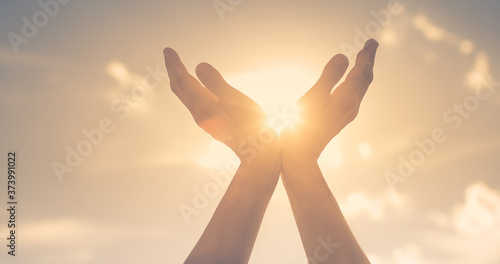 Hands reaching out to sky, warm sunshine in the palm of hands. 