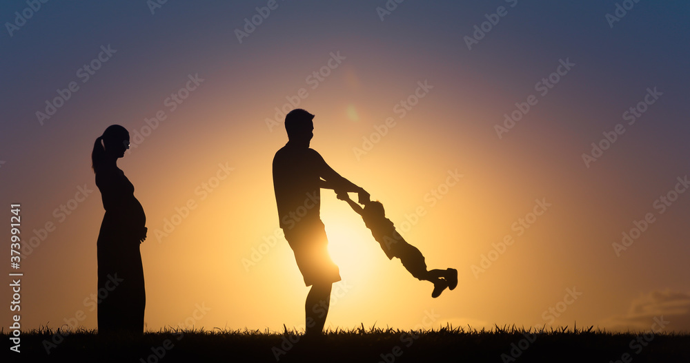Family playing together in the park at sunset 