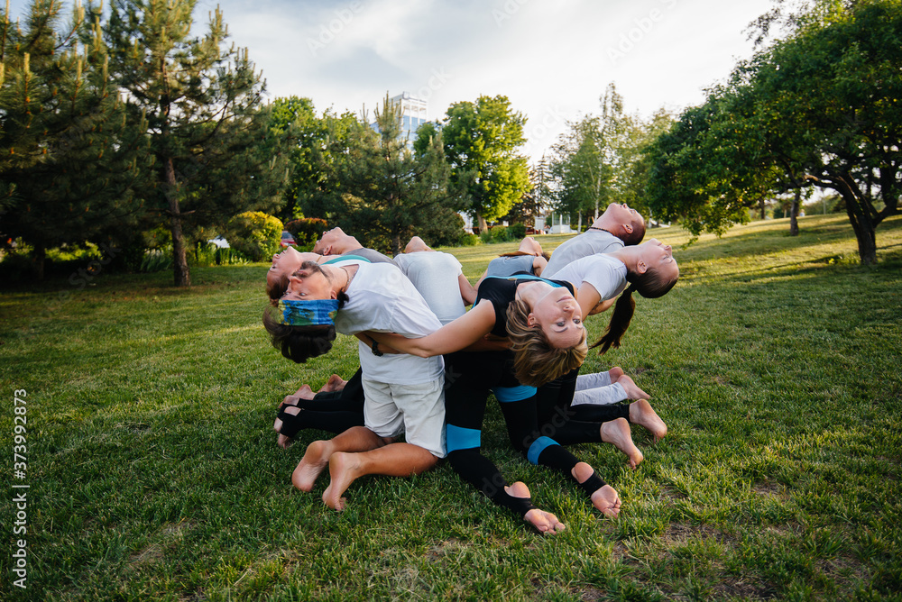 A group of people do yoga in a circle in the open air during sunset. Healthy lifestyle, meditation and Wellness A group of people do yoga in a circle in the open air during sunset. Healthy lifestyle, meditation and Wellness