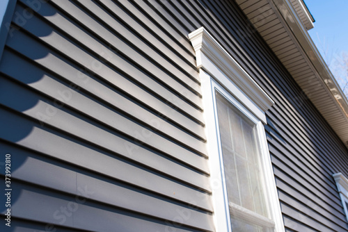 Dark vinyl siding in residential neighborhood, new window treatments photo