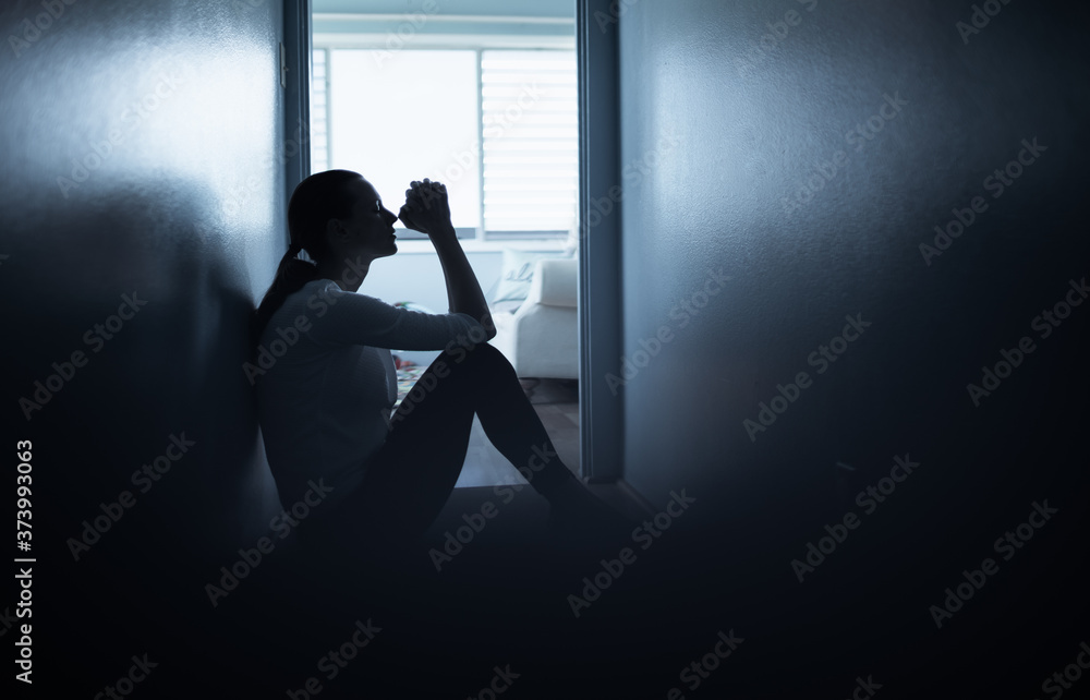 silhouette of a woman indoors next to window praying