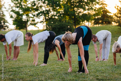 A group of people do yoga in the Park at sunset. Healthy lifestyle, meditation and Wellness